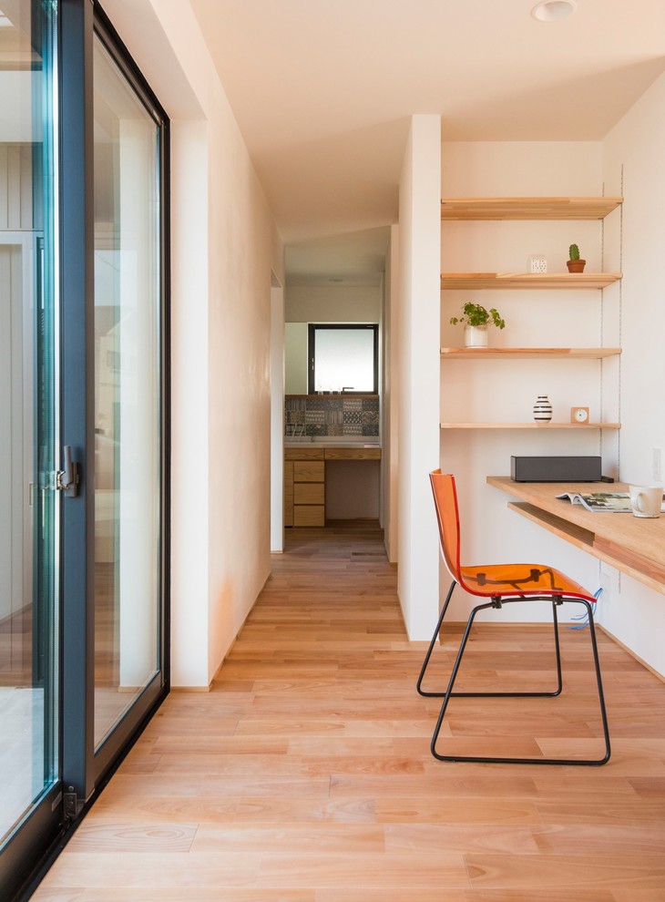 Idee per uno studio moderno con pareti bianche, pavimento in legno massello medio, scrivania incassata e pavimento marrone