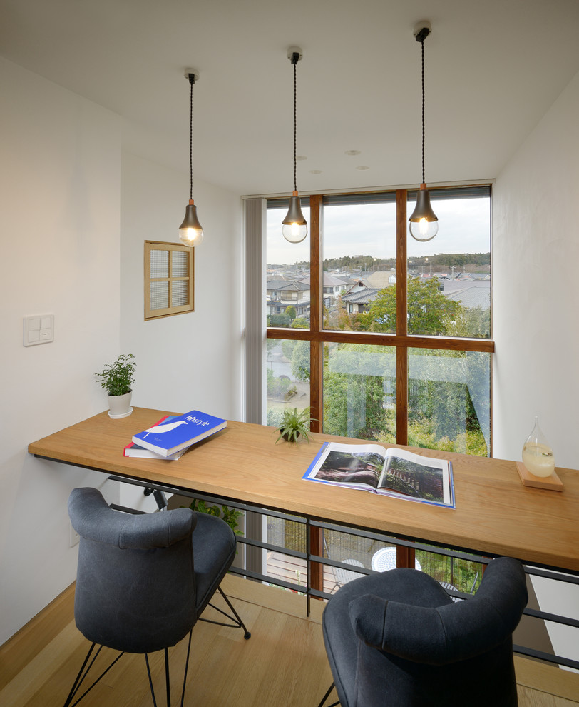 Modelo de despacho escandinavo pequeño sin chimenea con paredes blancas, suelo de madera clara y escritorio empotrado