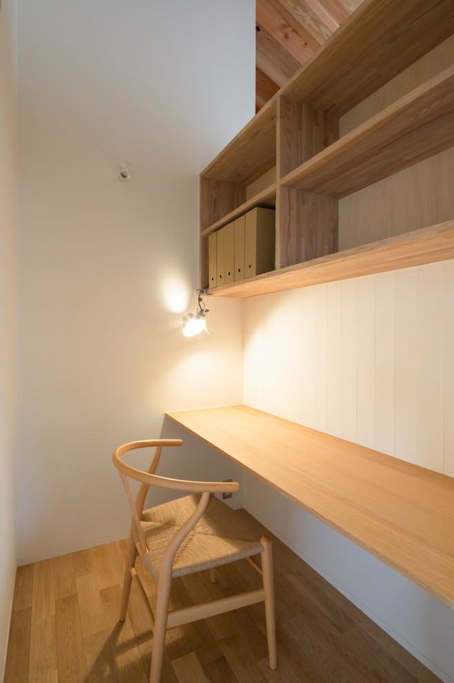 Medium sized scandinavian study in Nagoya with white walls, light hardwood flooring, a built-in desk and beige floors.