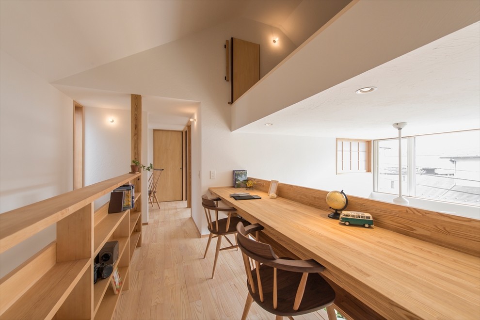 Imagen de despacho minimalista con paredes blancas, suelo de madera clara y suelo beige