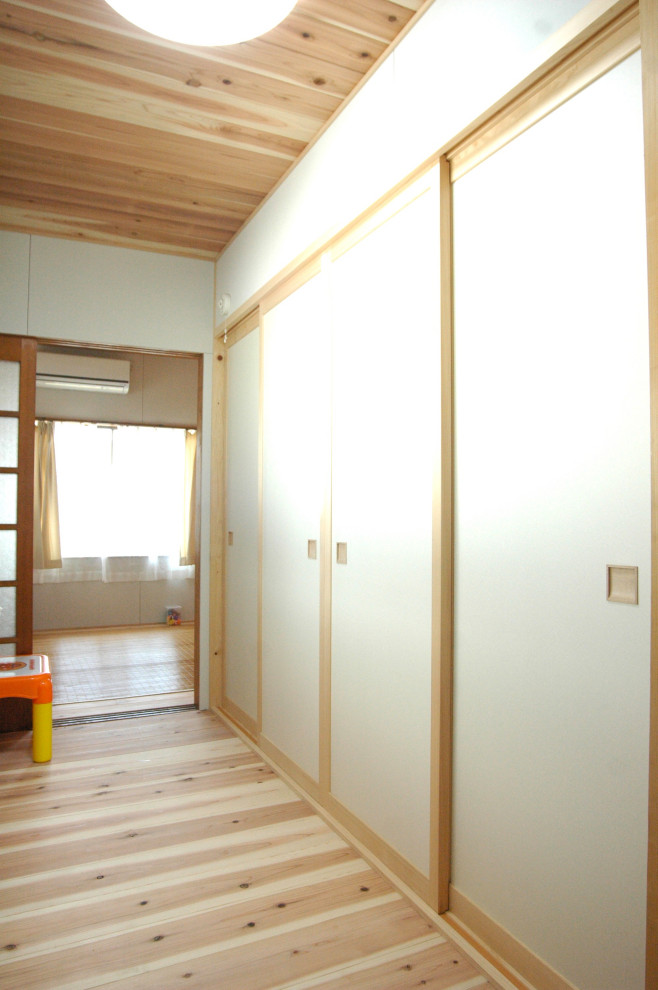 На фото: рабочее место среднего размера в восточном стиле с белыми стенами, паркетным полом среднего тона, встроенным рабочим столом, коричневым полом и деревянным потолком с