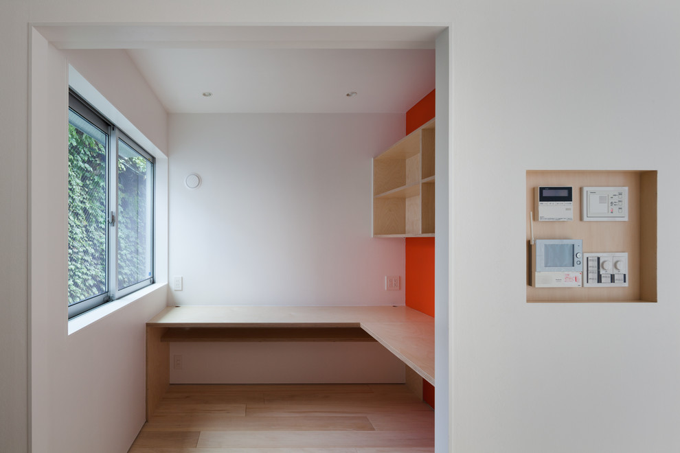 На фото: рабочее место в стиле модернизм с оранжевыми стенами, светлым паркетным полом, встроенным рабочим столом и бежевым полом без камина с