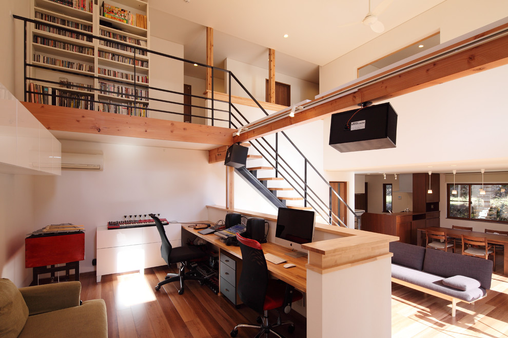Bild på ett funkis hemmastudio, med vita väggar, ljust trägolv, ett inbyggt skrivbord och brunt golv