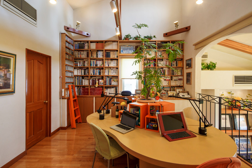 Ejemplo de despacho mediterráneo pequeño sin chimenea con biblioteca, paredes blancas y suelo de madera en tonos medios