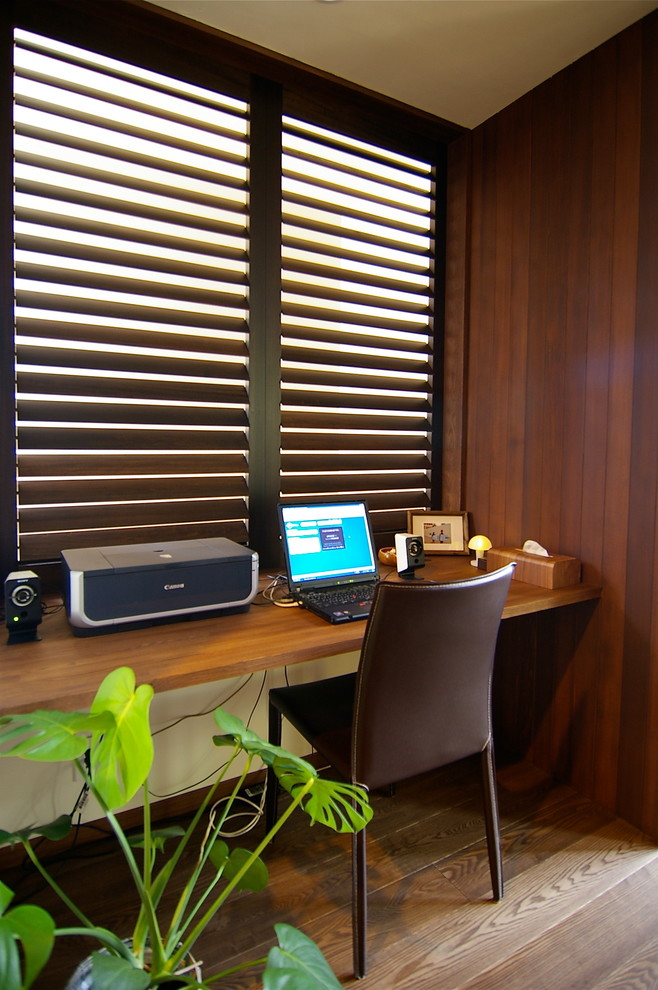 На фото: кабинет в стиле ретро с коричневыми стенами, темным паркетным полом, встроенным рабочим столом и коричневым полом