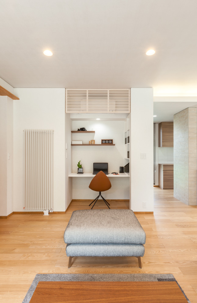Esempio di un piccolo studio moderno con pareti bianche, parquet chiaro, scrivania incassata e pavimento marrone
