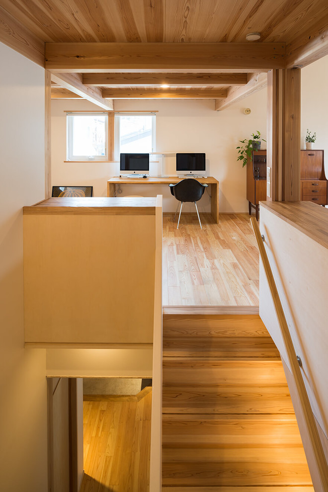 На фото: кабинет в восточном стиле с белыми стенами, светлым паркетным полом, встроенным рабочим столом и коричневым полом с
