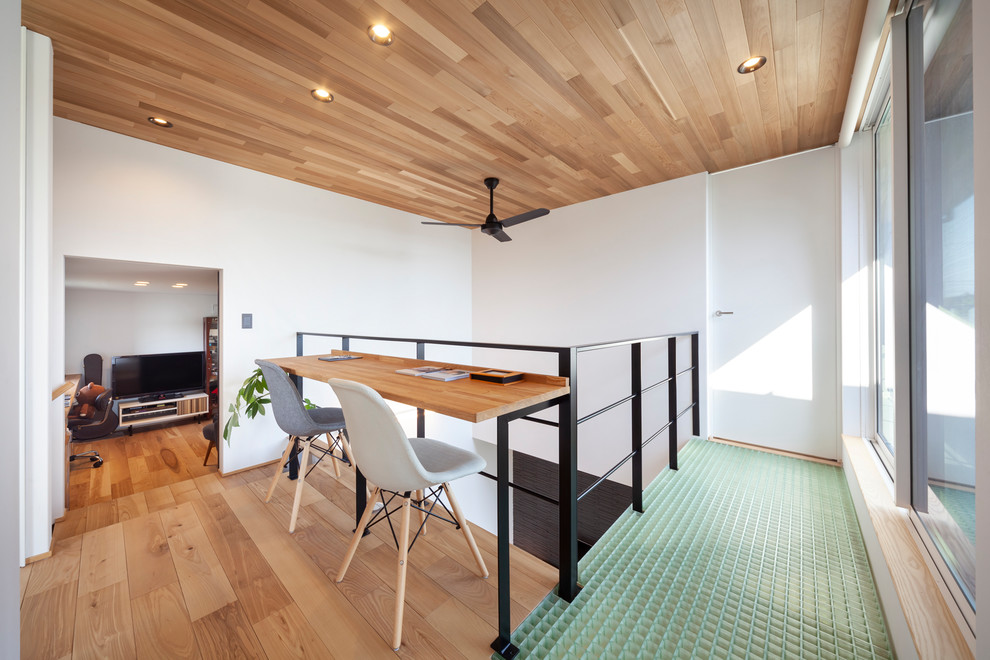 Immagine di un piccolo studio industriale con pareti bianche, stufa a legna, pavimento marrone, pavimento in legno massello medio e scrivania incassata