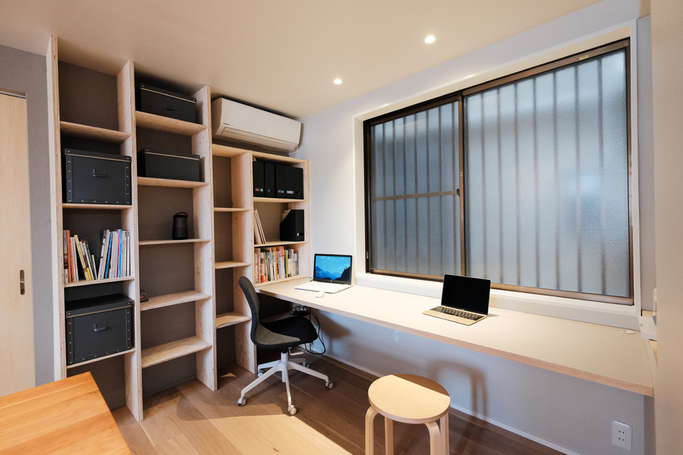 Foto de despacho urbano con paredes multicolor, suelo de madera clara, escritorio empotrado y suelo beige