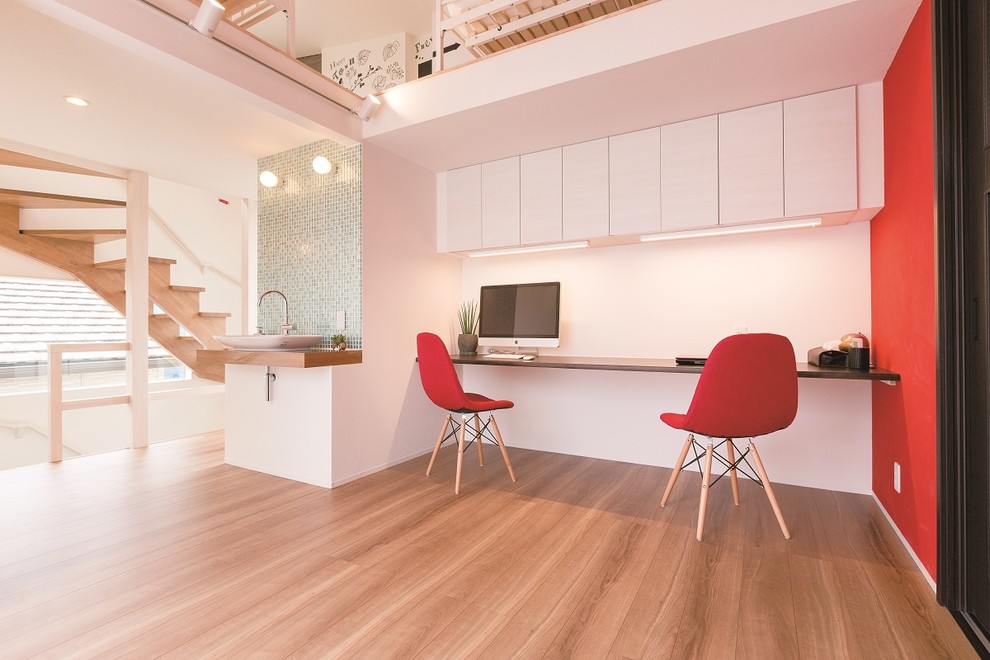 Bild på ett funkis arbetsrum, med flerfärgade väggar, ljust trägolv, ett inbyggt skrivbord och brunt golv