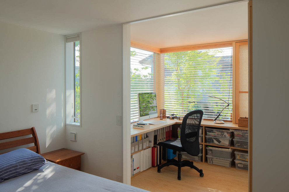 Exempel på ett mellanstort skandinaviskt hemmabibliotek, med vita väggar, ljust trägolv, en standard öppen spis, en spiselkrans i sten, ett inbyggt skrivbord och beiget golv
