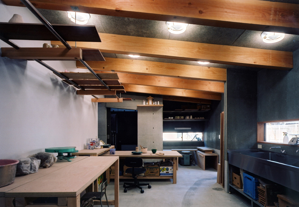 Foto de estudio minimalista de tamaño medio sin chimenea con paredes grises, suelo de cemento, escritorio independiente y suelo gris