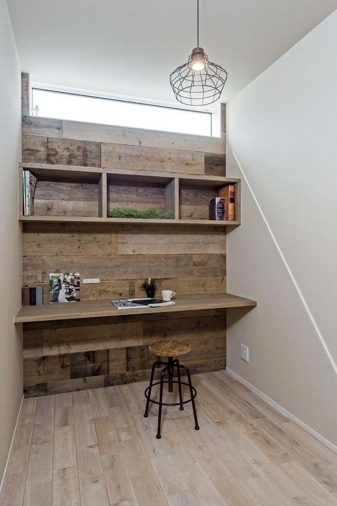 Industriell inredning av ett litet arbetsrum, med vita väggar, målat trägolv, ett inbyggt skrivbord och grått golv