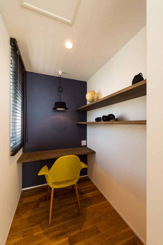 На фото: кабинет в современном стиле с разноцветными стенами, темным паркетным полом, встроенным рабочим столом и коричневым полом