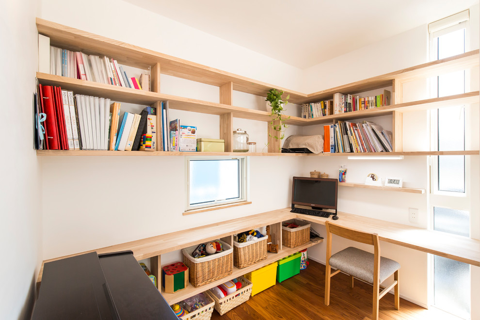 Asiatisches Arbeitszimmer mit weißer Wandfarbe, braunem Holzboden, Einbau-Schreibtisch und braunem Boden in Sonstige