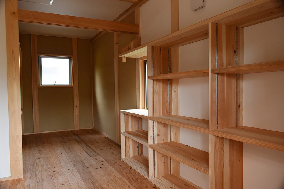 Asiatisk inredning av ett litet arbetsrum, med mellanmörkt trägolv och vita väggar