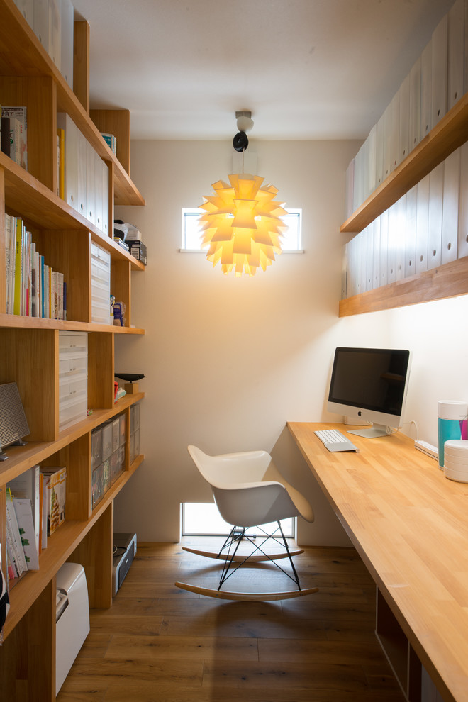 Modelo de despacho actual con paredes blancas, suelo de madera en tonos medios, escritorio empotrado y suelo marrón