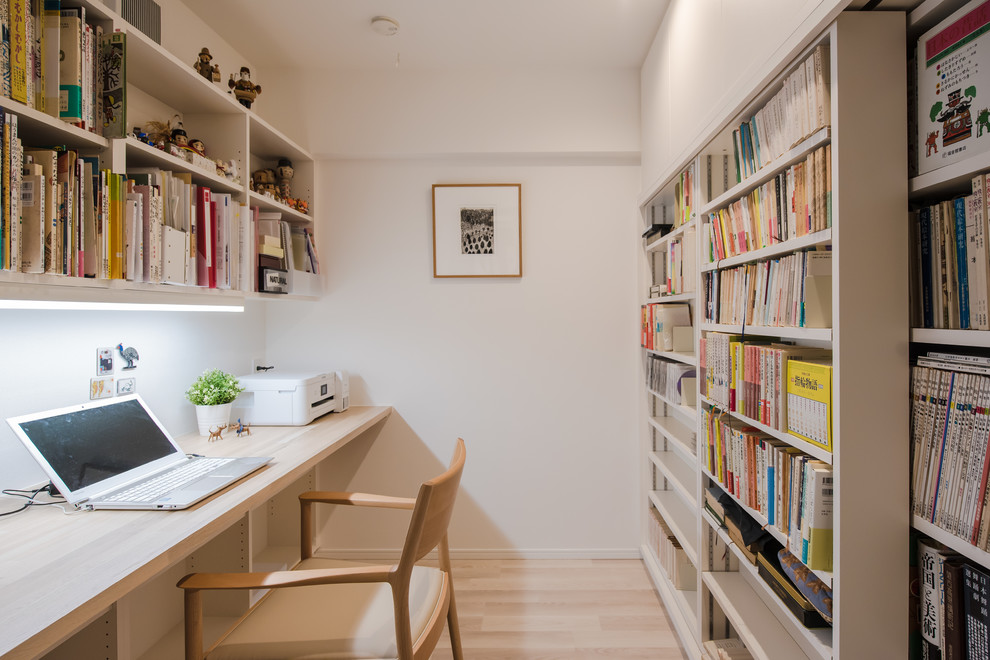 Immagine di uno studio minimalista con pareti bianche, nessun camino, scrivania incassata e pavimento beige