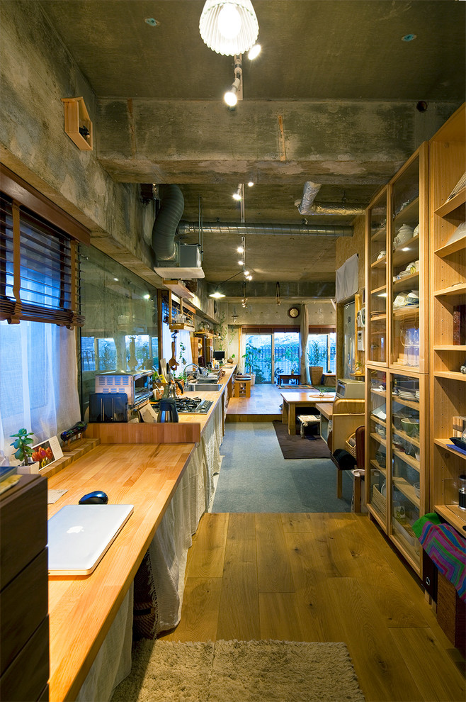 Mittelgroßes Industrial Arbeitszimmer ohne Kamin mit Arbeitsplatz, grauer Wandfarbe, braunem Holzboden und Einbau-Schreibtisch in Sonstige