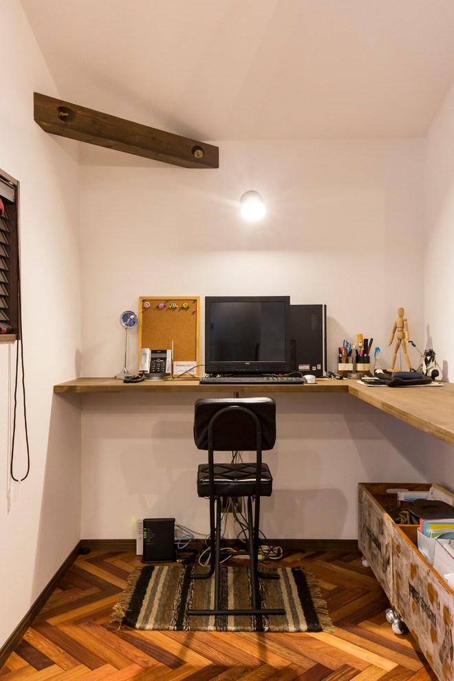 他の地域にある小さなコンテンポラリースタイルのおしゃれなホームオフィス・書斎 (白い壁、濃色無垢フローリング、造り付け机、茶色い床) の写真