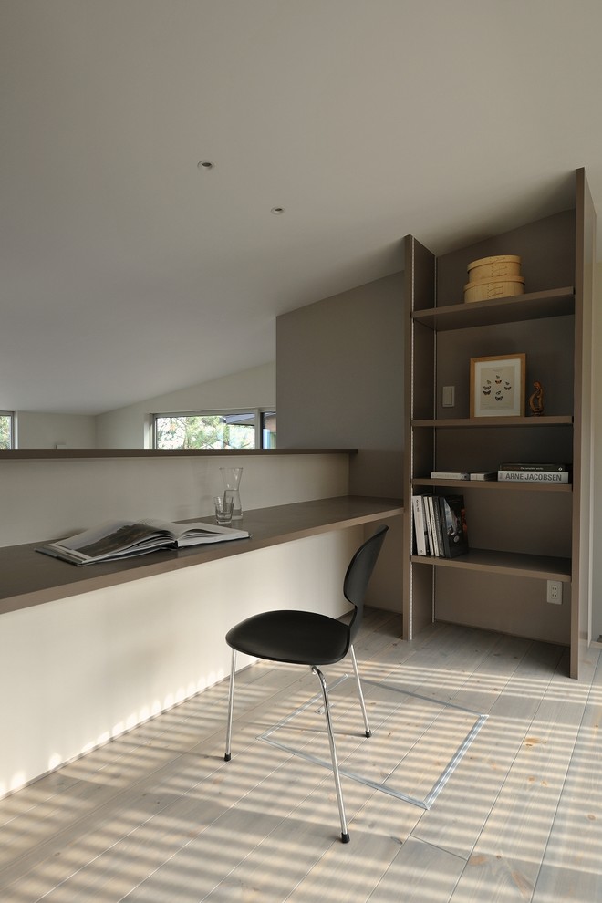 Modernes Arbeitszimmer mit grauer Wandfarbe, gebeiztem Holzboden, Einbau-Schreibtisch und grauem Boden in Sonstige