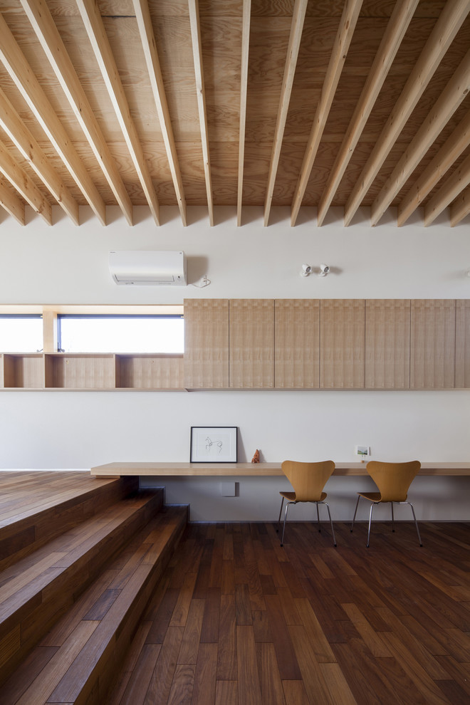 Ejemplo de despacho minimalista sin chimenea con paredes blancas, suelo de madera oscura, escritorio empotrado y suelo marrón