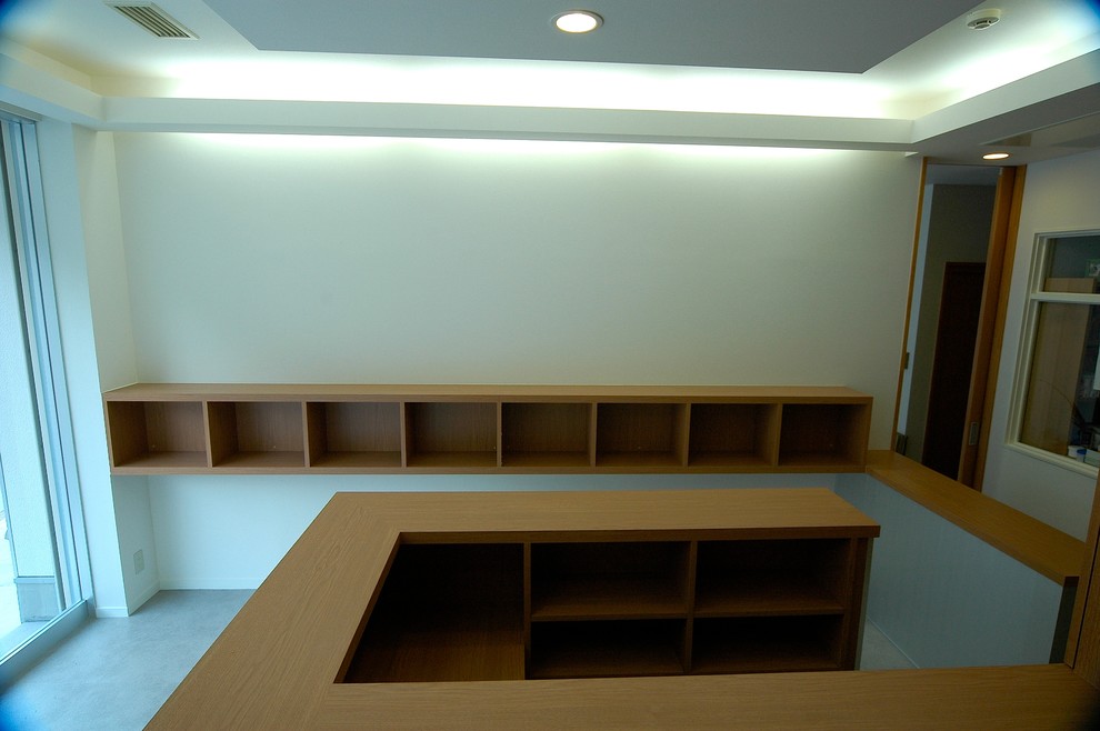 Inredning av ett modernt arbetsrum, med vita väggar, betonggolv, ett inbyggt skrivbord och vitt golv