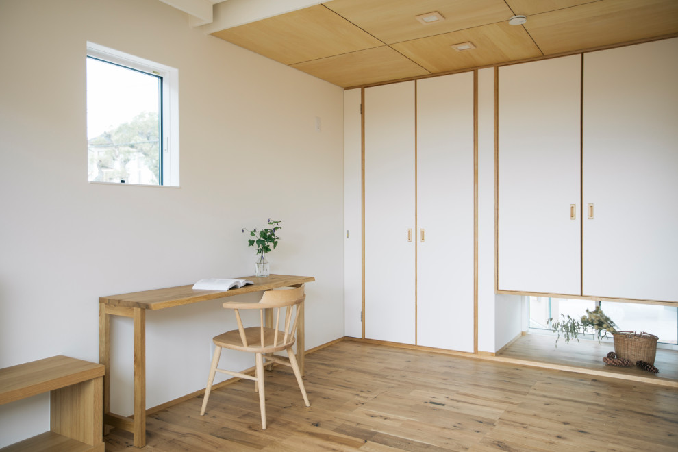 Inspiration för mellanstora asiatiska hemmabibliotek, med vita väggar, ett fristående skrivbord, beiget golv och mellanmörkt trägolv