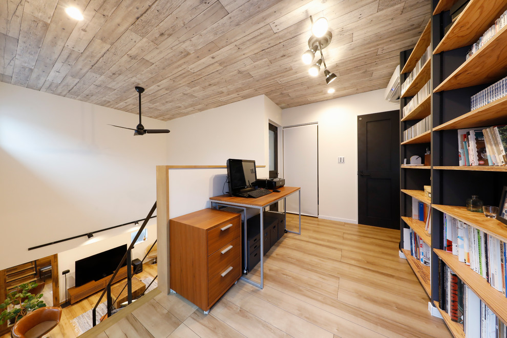 Cette image montre un bureau asiatique avec un mur blanc, un sol en bois brun, un bureau indépendant et un sol marron.