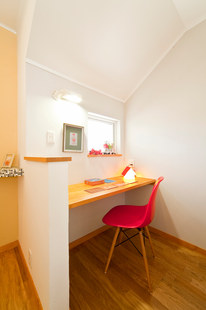 Immagine di un piccolo ufficio nordico con pareti bianche, pavimento in legno massello medio e scrivania incassata