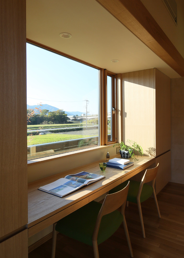 Asiatisches Arbeitszimmer mit beiger Wandfarbe, braunem Holzboden, Einbau-Schreibtisch und braunem Boden in Sonstige