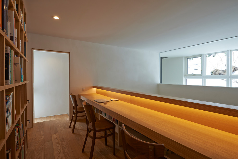 Asiatisches Lesezimmer mit weißer Wandfarbe, hellem Holzboden, Einbau-Schreibtisch und beigem Boden