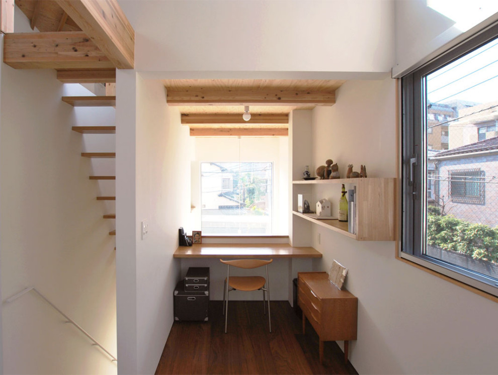 Kleines Modernes Arbeitszimmer ohne Kamin mit Arbeitsplatz, weißer Wandfarbe, Sperrholzboden, Einbau-Schreibtisch, braunem Boden, freigelegten Dachbalken und Tapetenwänden in Fukuoka