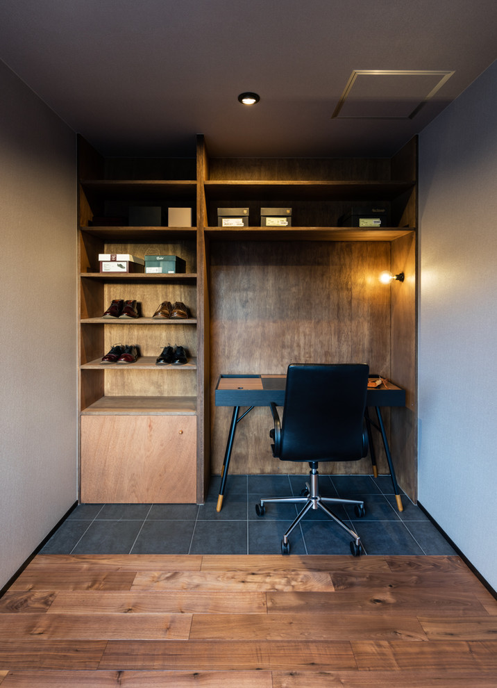Immagine di un piccolo studio minimalista con pareti bianche, scrivania autoportante e pavimento grigio