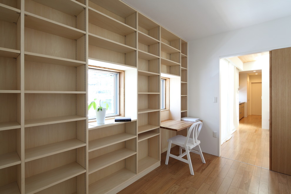 Imagen de estudio moderno sin chimenea con paredes blancas, suelo de contrachapado, escritorio empotrado y suelo beige