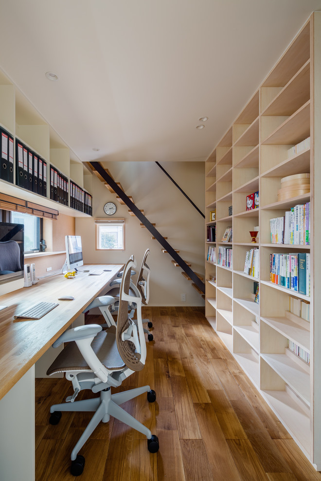 Skandinavisches Arbeitszimmer mit weißer Wandfarbe, braunem Holzboden, Einbau-Schreibtisch und braunem Boden in Sonstige