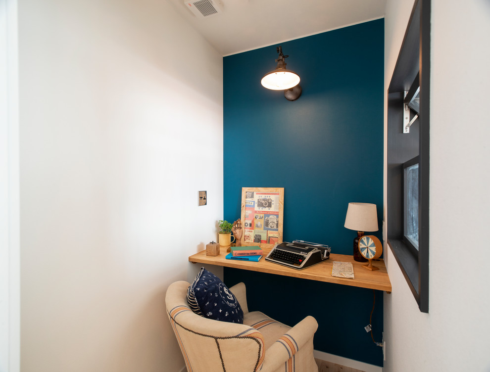 Bild på ett mellanstort maritimt arbetsrum, med blå väggar, ljust trägolv, ett inbyggt skrivbord och vitt golv