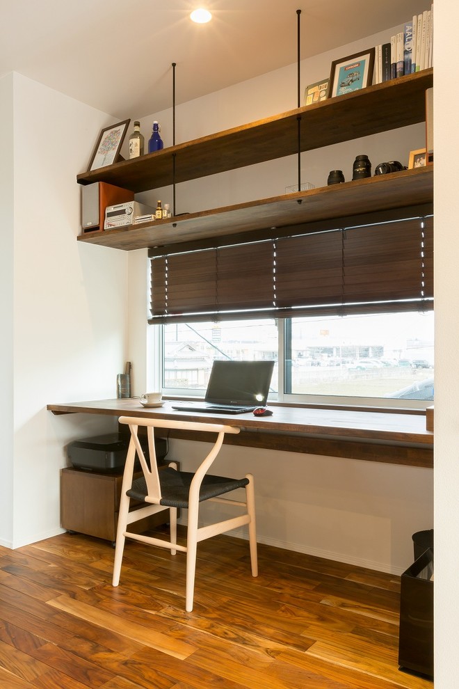 Asiatisk inredning av ett arbetsrum, med vita väggar, mellanmörkt trägolv, ett inbyggt skrivbord och brunt golv
