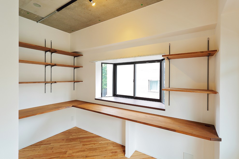 Idéer för mellanstora lantliga arbetsrum, med ett bibliotek, vita väggar, ljust trägolv och ett inbyggt skrivbord