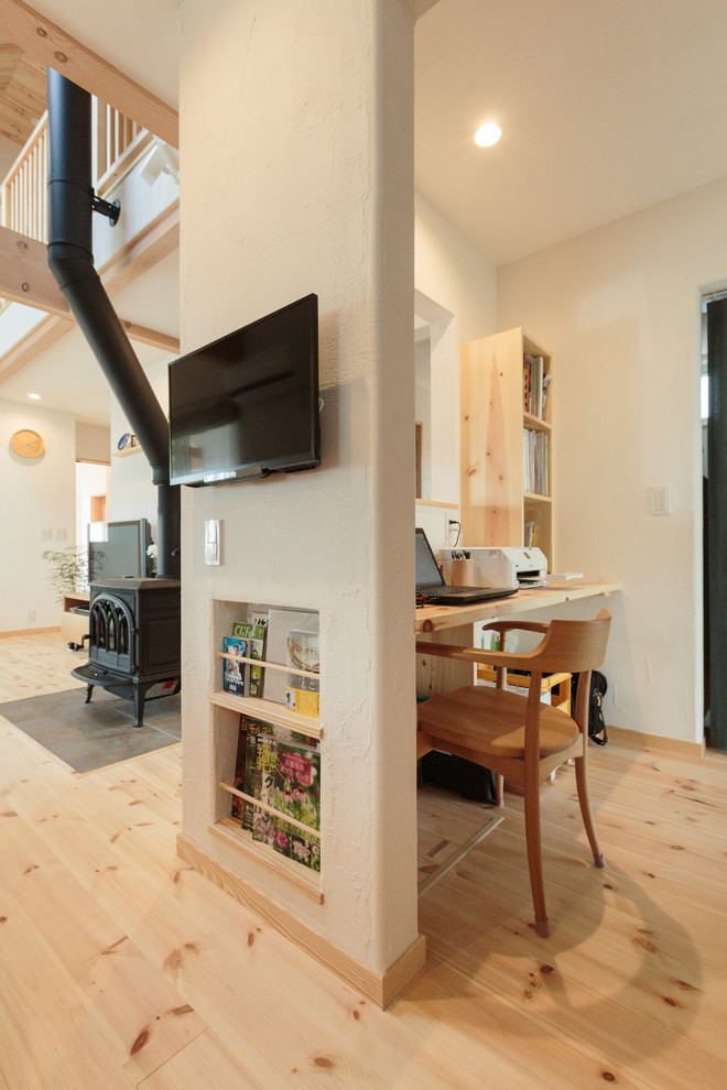 Foto de despacho rústico con paredes blancas, suelo de madera clara, estufa de leña, escritorio empotrado y suelo marrón
