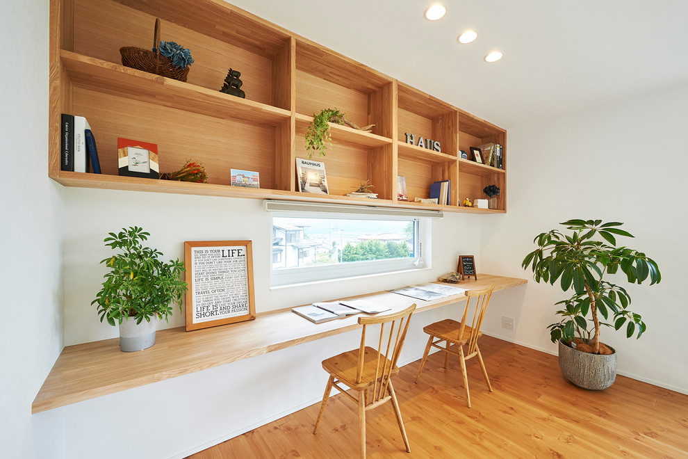 Ejemplo de despacho escandinavo de tamaño medio con biblioteca, paredes blancas, suelo de madera clara y suelo multicolor