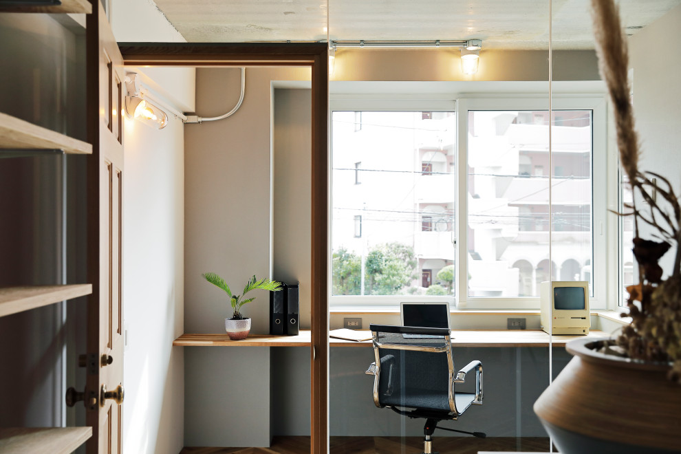 Modernes Arbeitszimmer ohne Kamin mit Arbeitsplatz, weißer Wandfarbe und braunem Holzboden in Tokio