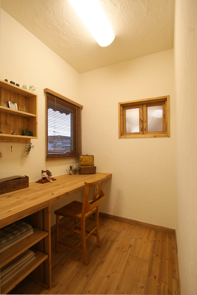 Foto på ett medelhavsstil arbetsrum, med vita väggar, mellanmörkt trägolv, ett inbyggt skrivbord och brunt golv