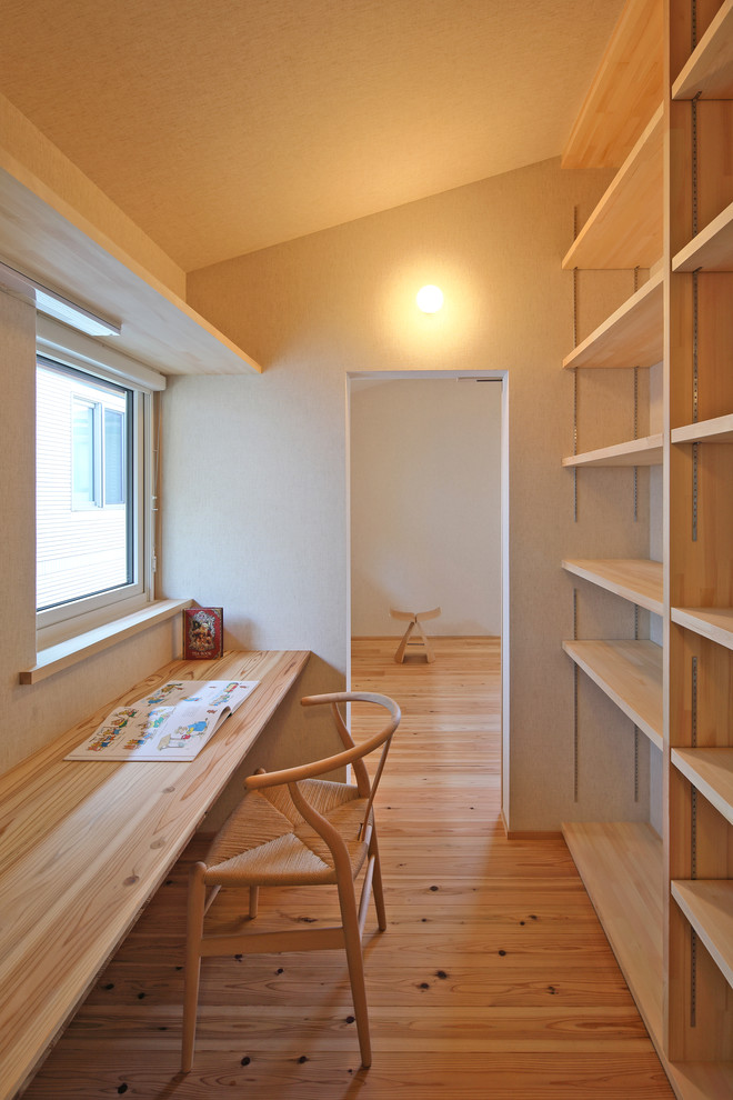 Idée de décoration pour un bureau minimaliste avec un mur blanc, un sol en bois brun et un bureau intégré.
