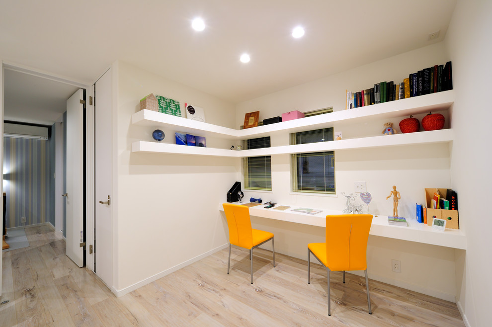 На фото: кабинет в стиле модернизм с белыми стенами, деревянным полом, встроенным рабочим столом и бежевым полом