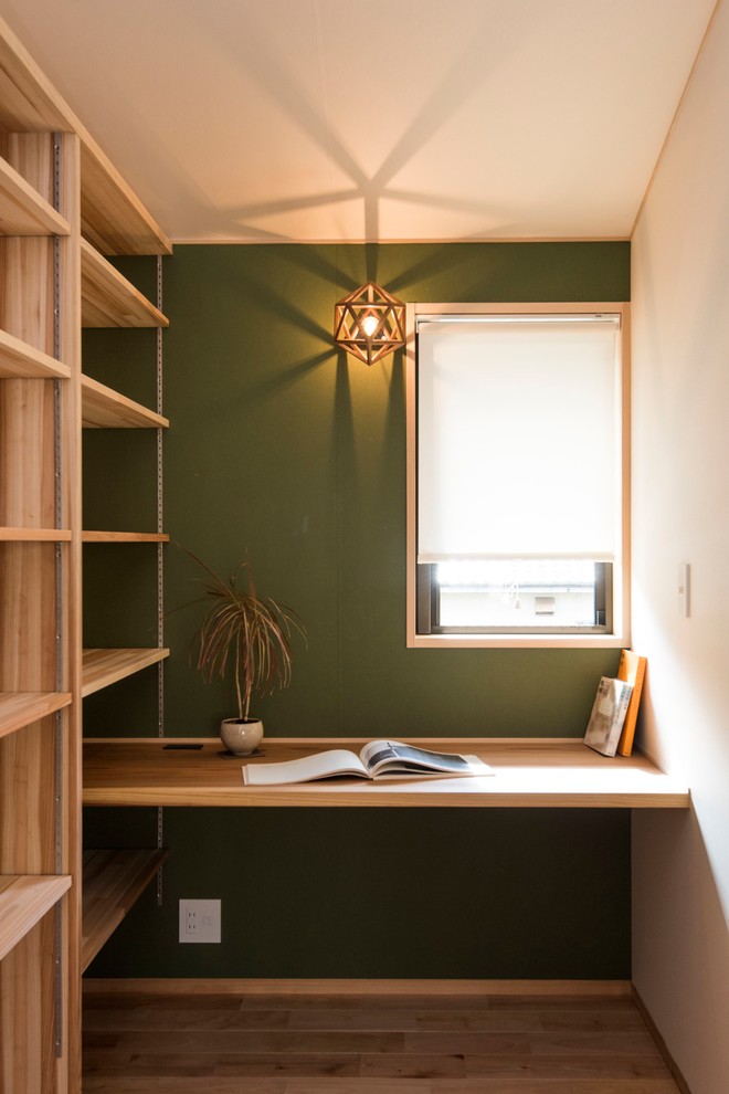 Industrial Arbeitszimmer mit Arbeitsplatz, grüner Wandfarbe, braunem Holzboden, Einbau-Schreibtisch und braunem Boden in Sonstige