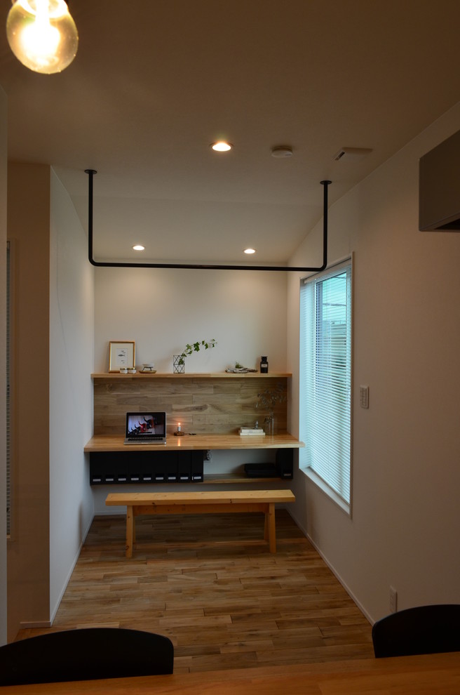 Exemple d'un petit bureau scandinave avec un mur blanc, un sol en bois brun, aucune cheminée, un bureau intégré et un sol marron.