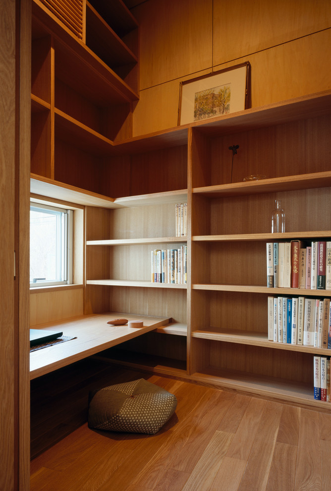 Bild på ett litet orientaliskt hemmabibliotek, med bruna väggar, ljust trägolv och ett inbyggt skrivbord