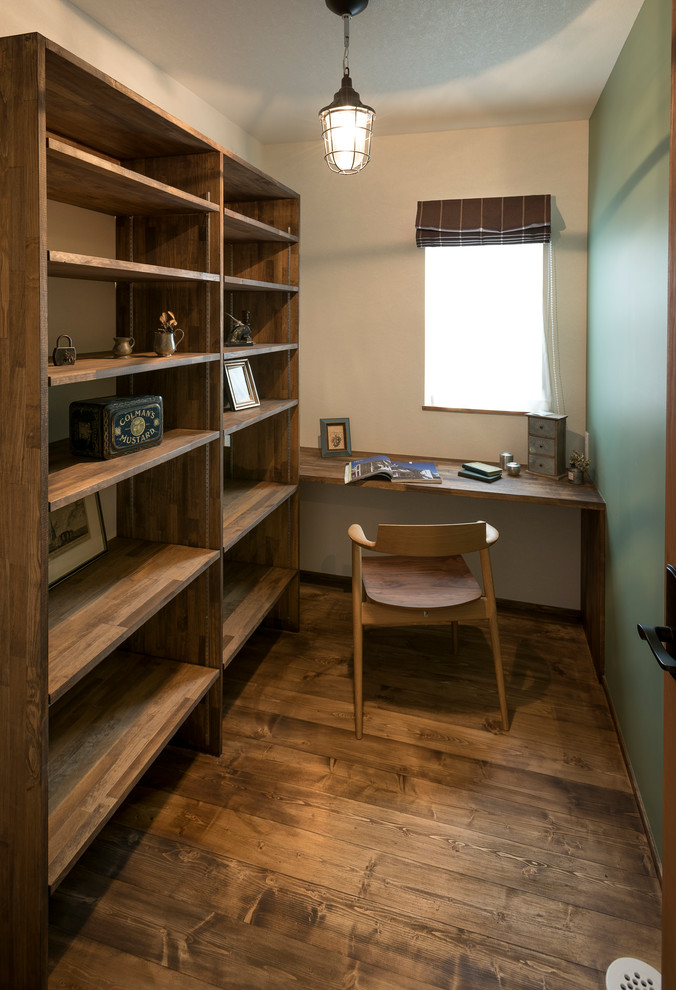 Réalisation d'un bureau asiatique avec un mur bleu, un sol en bois brun, un bureau intégré et un sol marron.