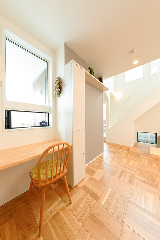 Small scandinavian craft room in Tokyo Suburbs with white walls, medium hardwood flooring, a built-in desk and brown floors.